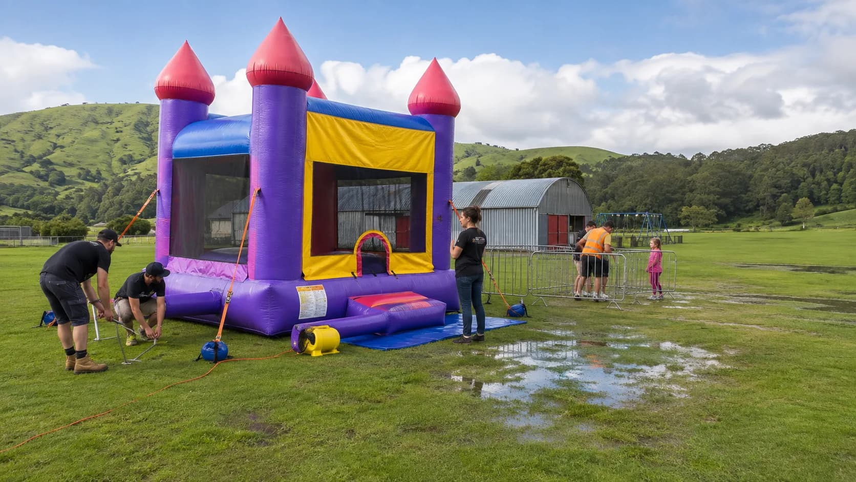 Operator setting a bouncy castle on wet New Zealand grass