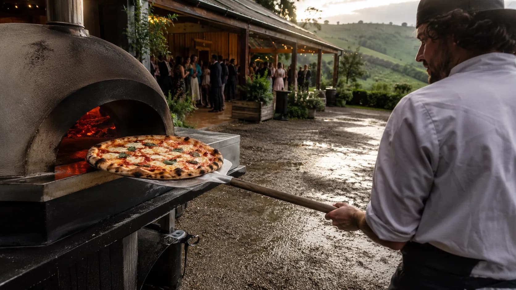 New Zealand pizza caterer working beside a rainy timber wedding venue