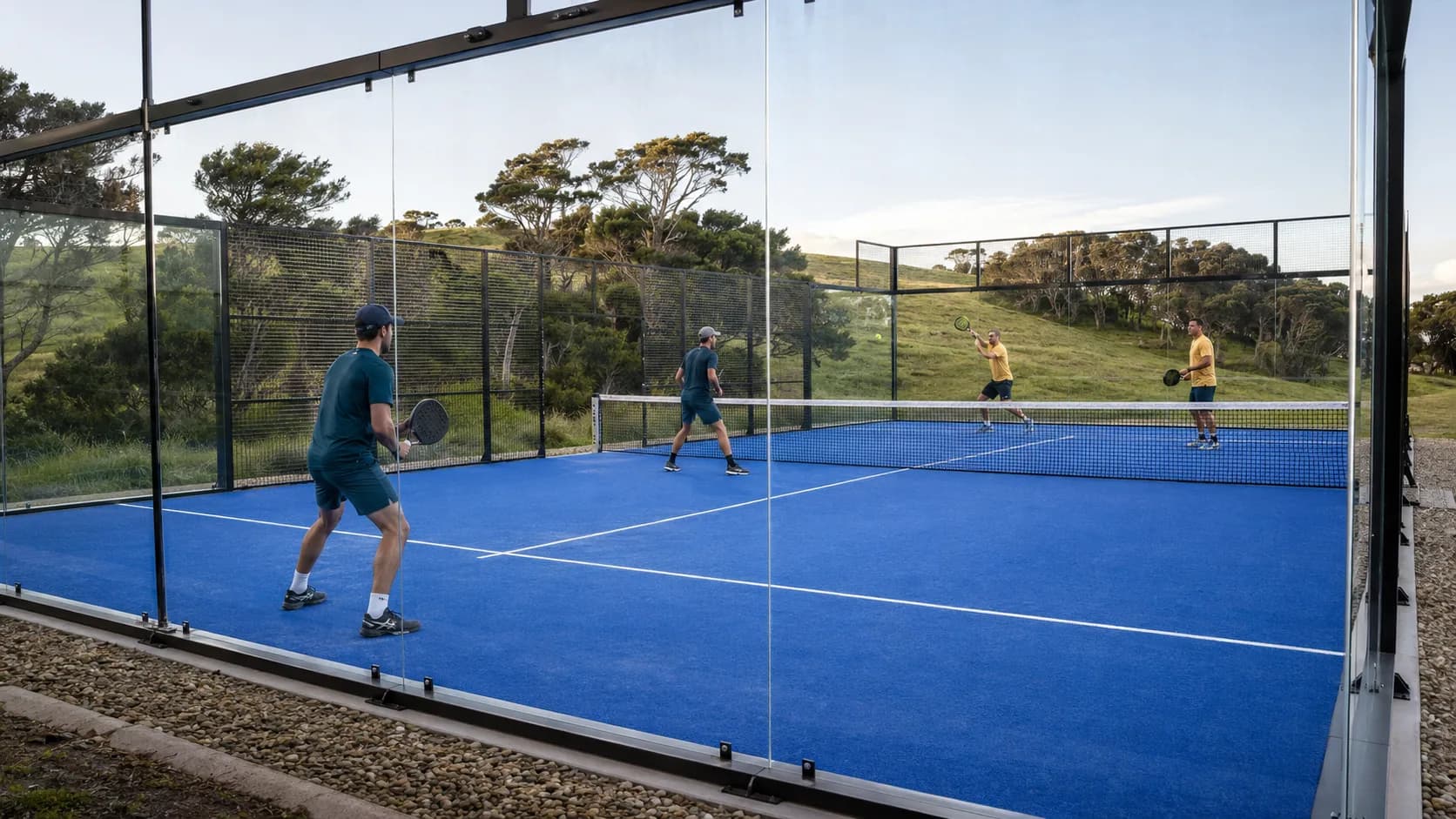 A glass-walled padel court at a New Zealand club, lit and ready for evening doubles