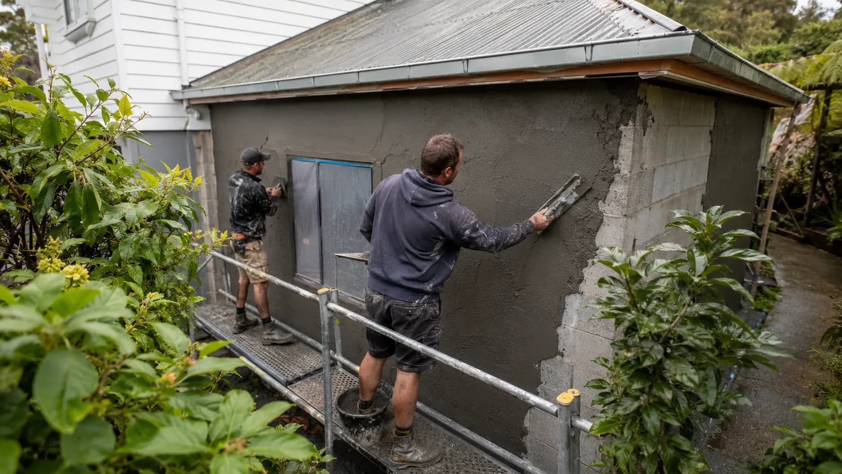 A renderer floating a coat of render onto a house wall in New Zealand