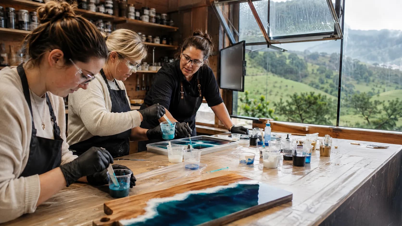 An artist tutor guides a resin pour at ventilated workshop stations in New Zealand