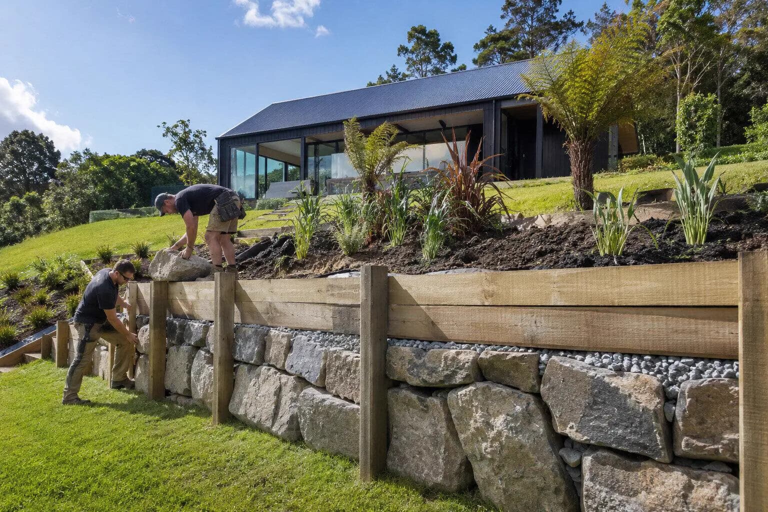 A builder setting a retaining wall in a sloping back garden in New Zealand