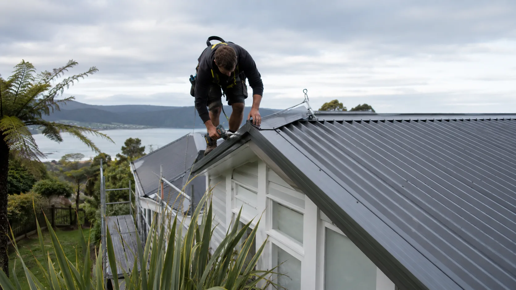 A roofer at work on a house roof in New Zealand