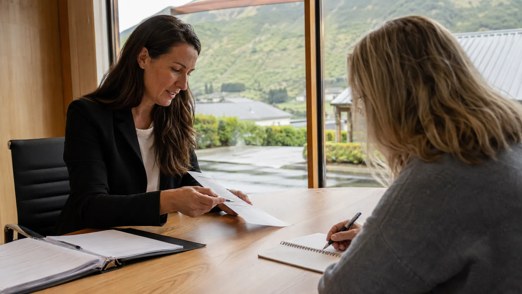 A solicitor discusses a legal document with a client in New Zealand