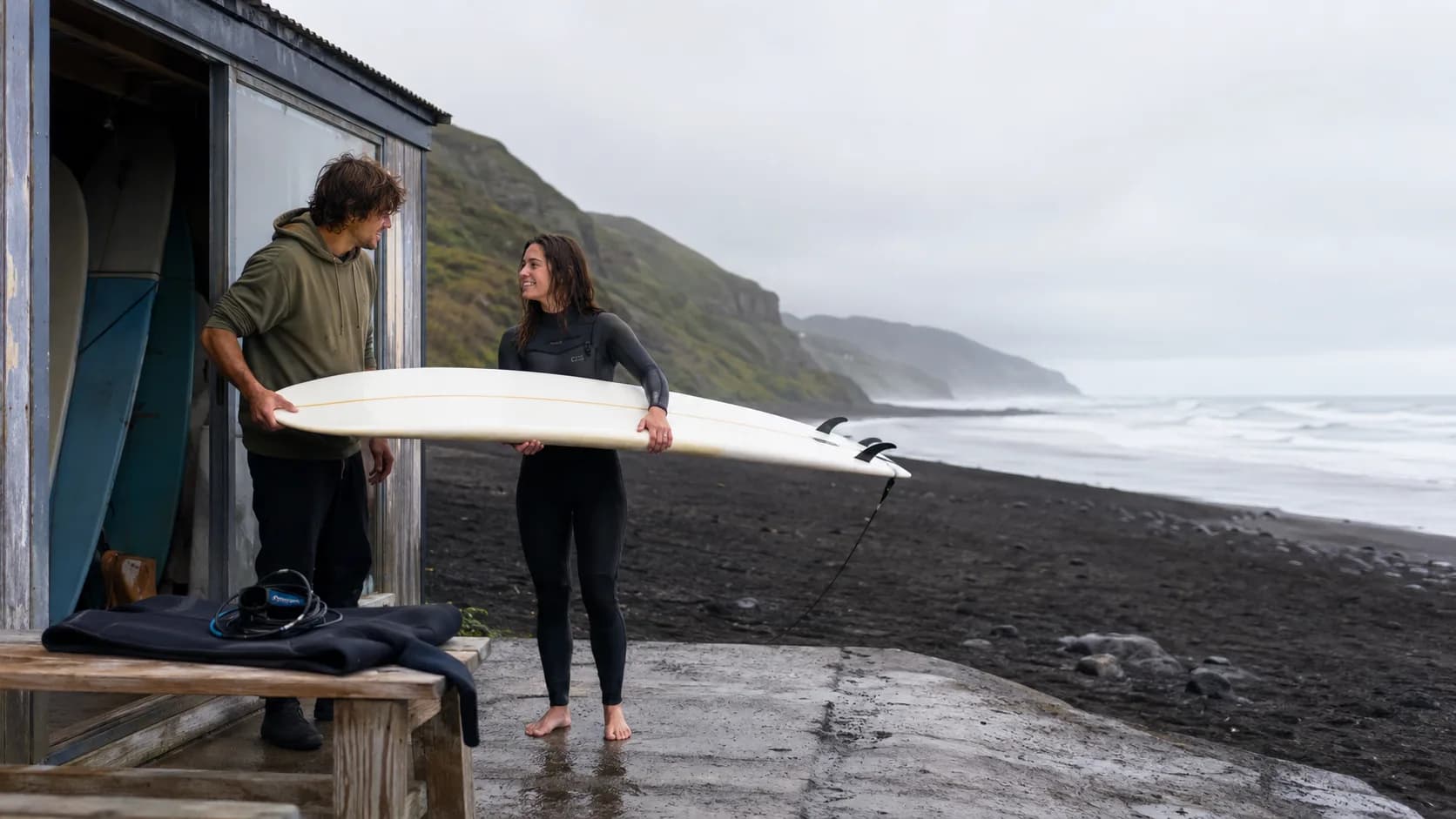 Surfer receiving a board outside a coastal shop in New Zealand