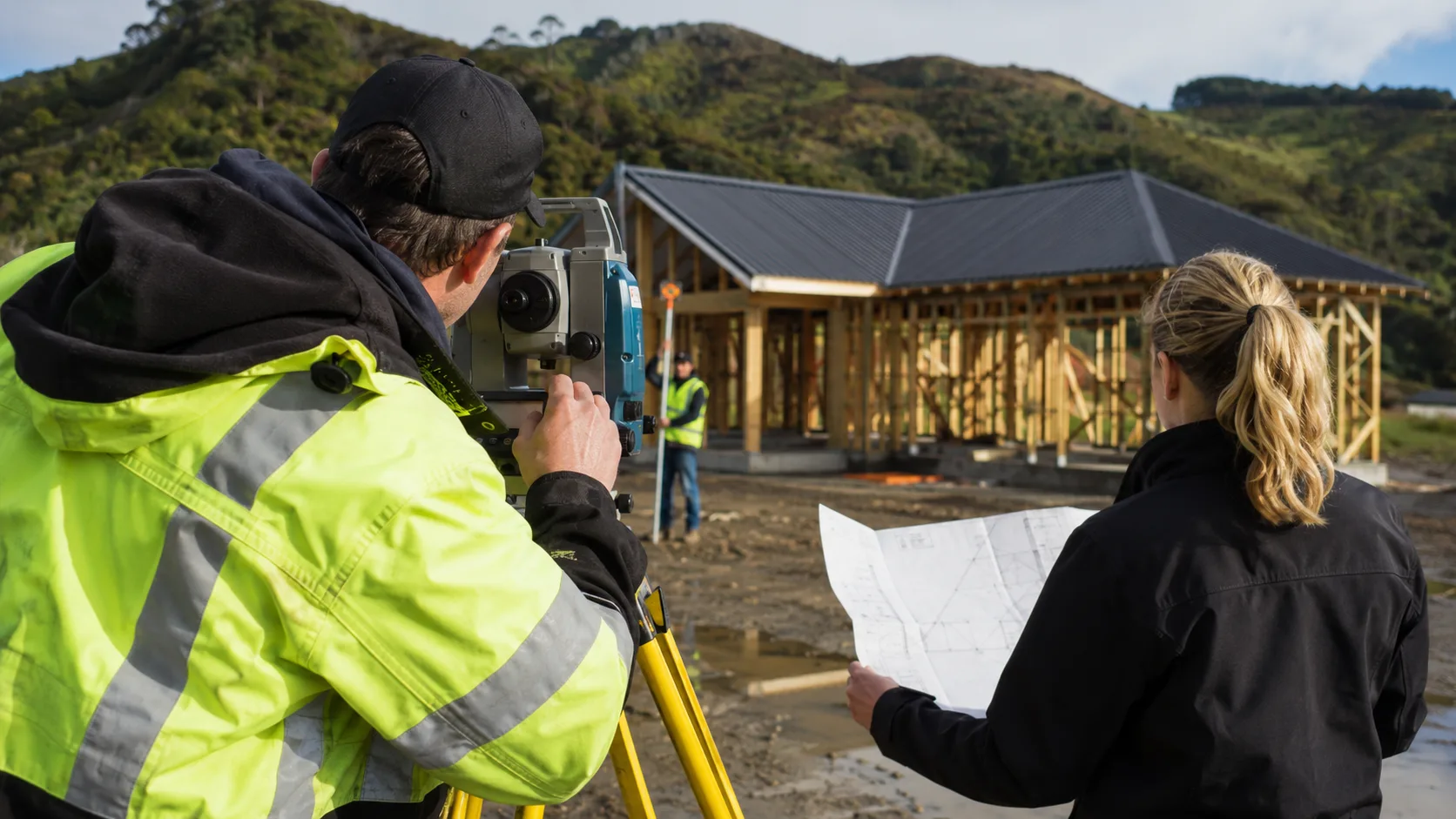 A surveyor takes site measurements using professional equipment in New Zealand