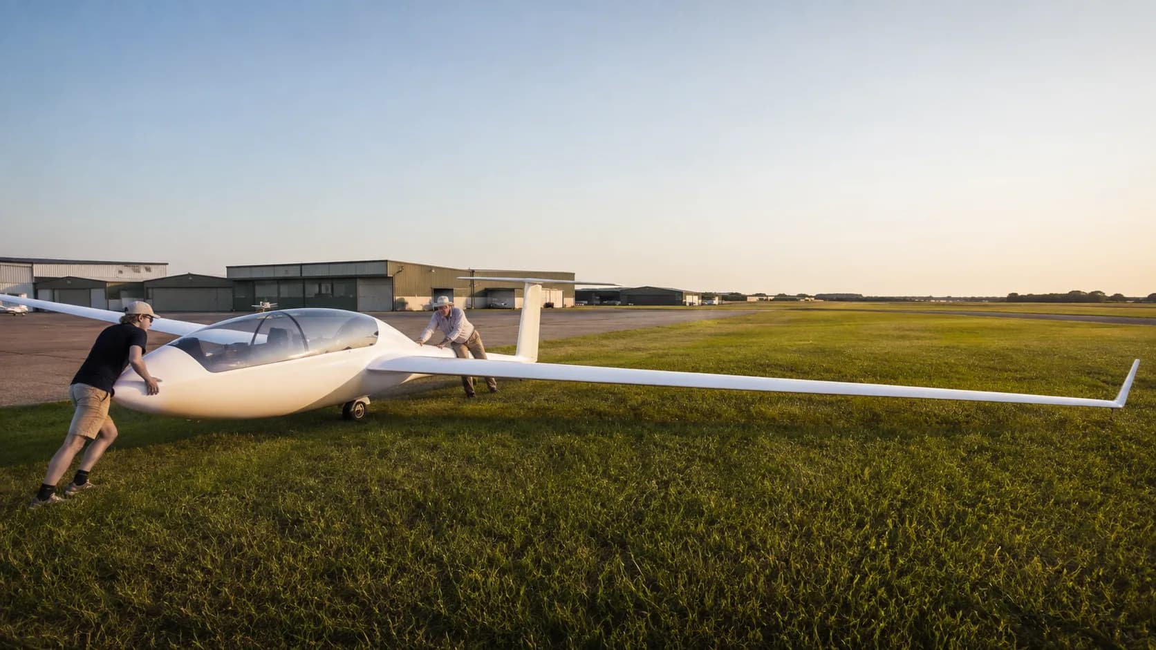 A sailplane waits on a US gliderport ramp with a tow plane ahead of it