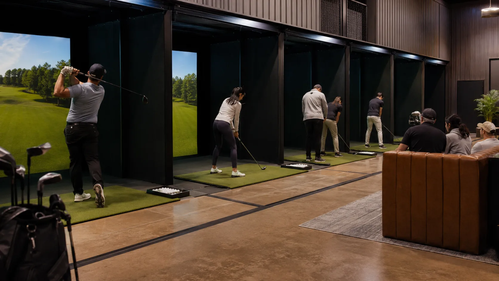 Golfers fill several commercial simulator bays inside a venue in the US