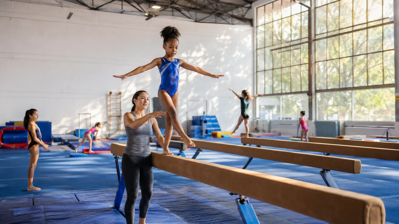 Youth gymnastics class practising skills with coaches in a gym in the US