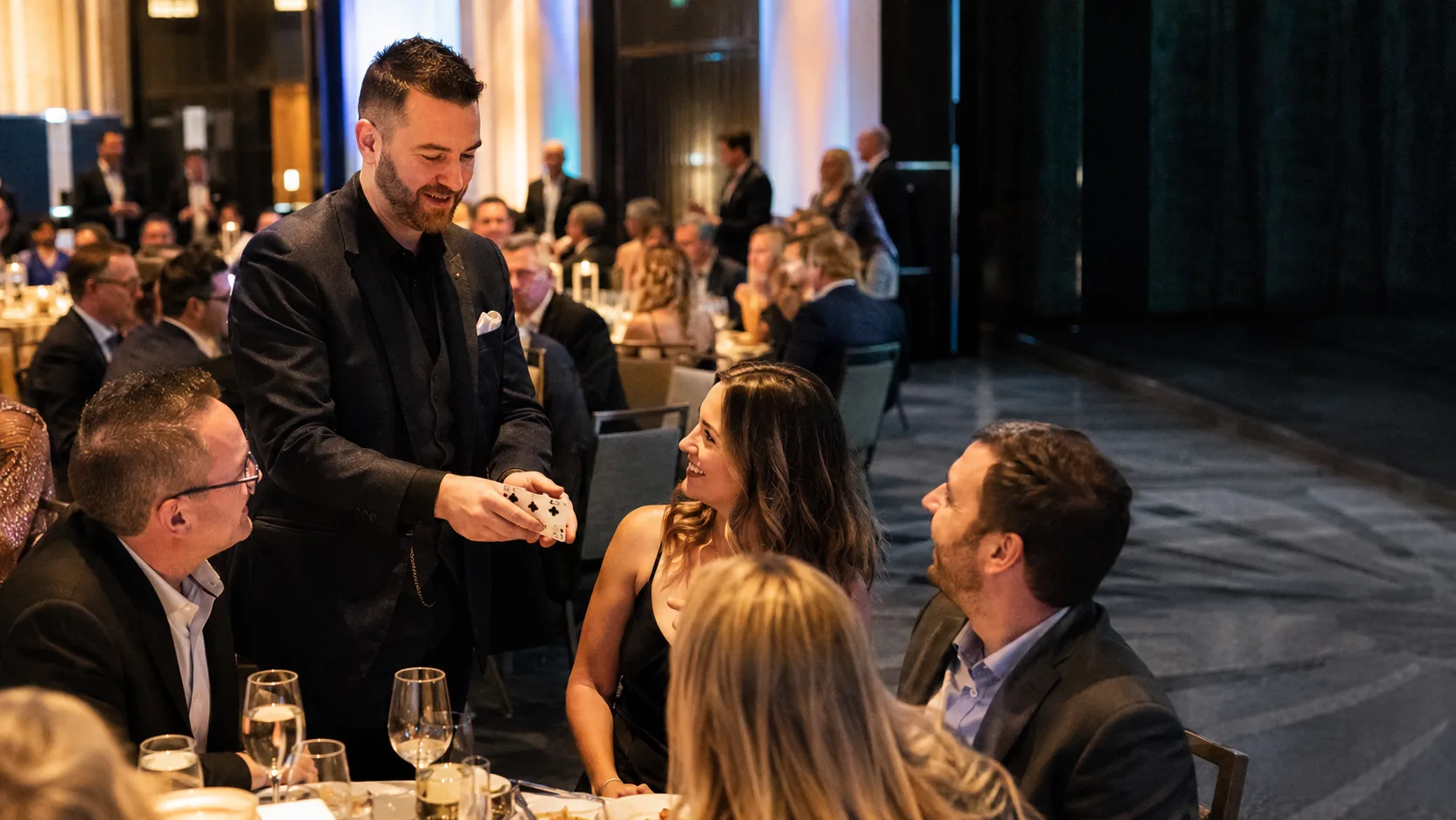 Magician performing close-up magic for delighted event guests in the US