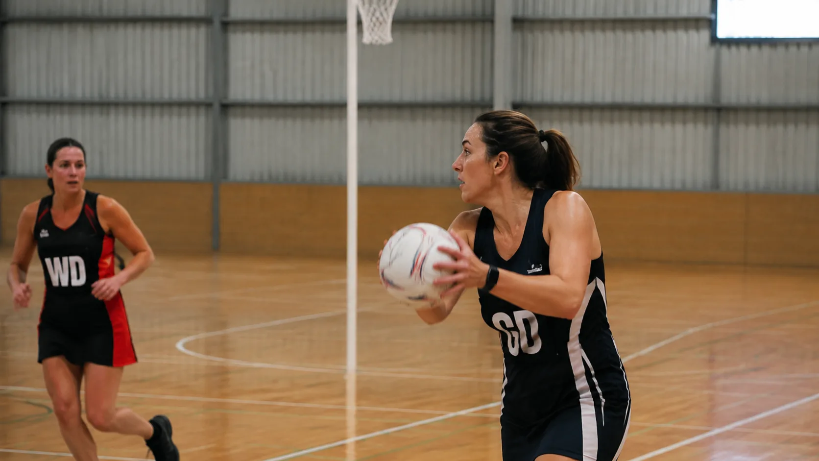 An indoor gym court set up for netball at a US community facility, lined and lit for evening rentals