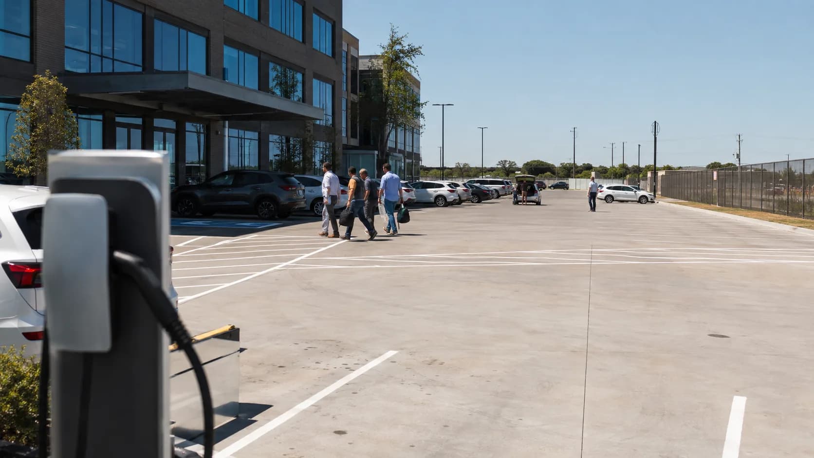 Cars fill a bright office parking lot around a shaded entrance