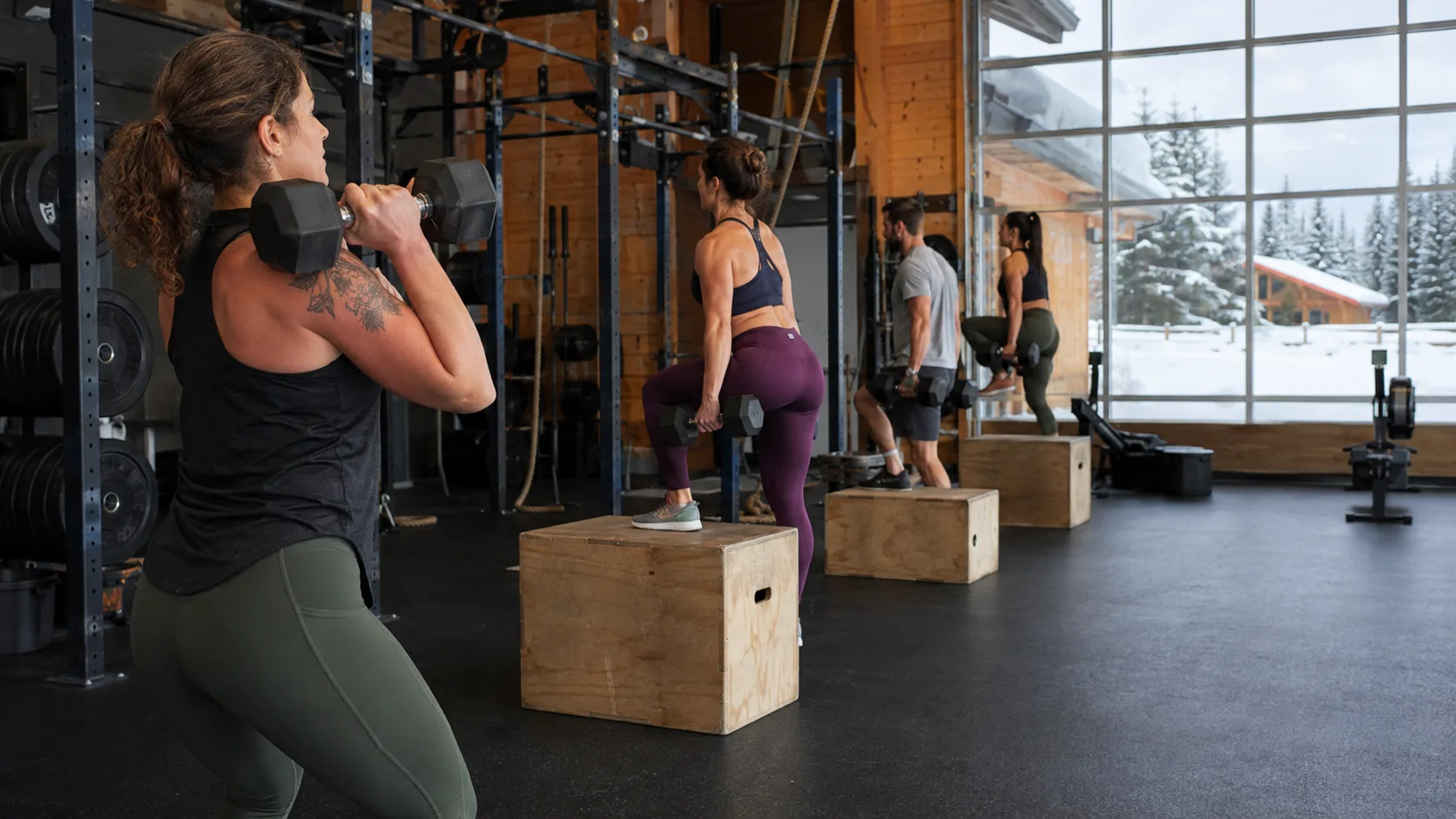 Athletes rowing and lifting in a warm gym bay with snow beyond the door in Canada